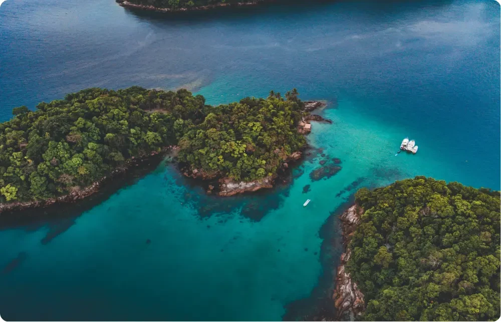 Vue a&eacute;rienne de la Costa Verde au Br&eacute;sil : &icirc;lots couverts de jungle tropicale entour&eacute;s d&rsquo;eaux turquoise, voilier au mouillage pr&egrave;s d&rsquo;Ilha Grande, destination id&eacute;ale pour une croisi&egrave;re entre Paraty et plages pr&eacute;serv&eacute;es.