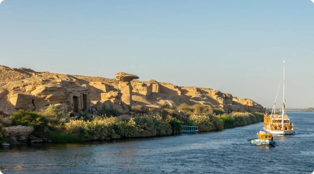 Dahabieh naviguant sur le Nil le long des carrières de grès de Gebel Silsileh, entre Edfou et Kôm Ombo en Égypte, au coucher du soleil