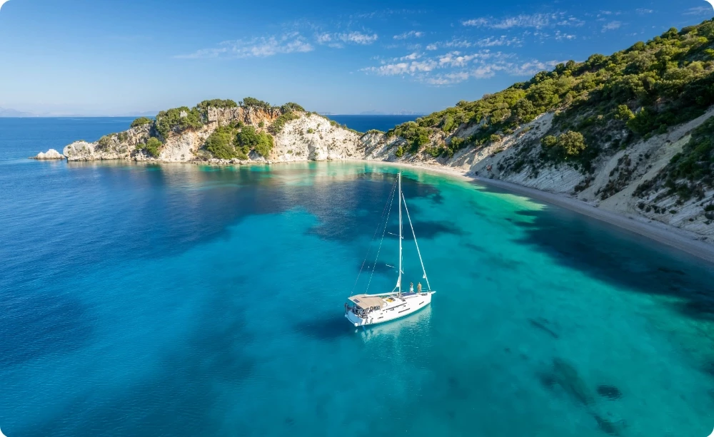 Barca a vela all'ancora in una caletta greca dalle acque turchesi e blu intenso