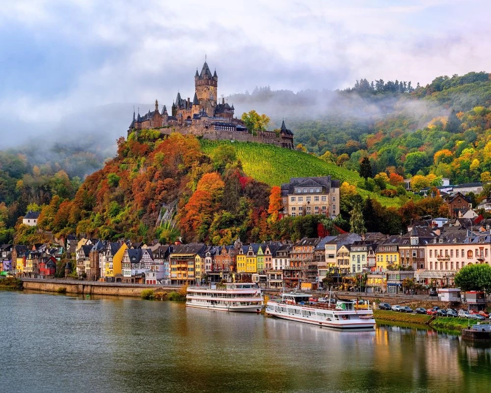 Bateau de croisi&egrave;re fluviale &agrave; Cochem, sur la Moselle, au pied du ch&acirc;teau de Cochem et de ses vignobles
