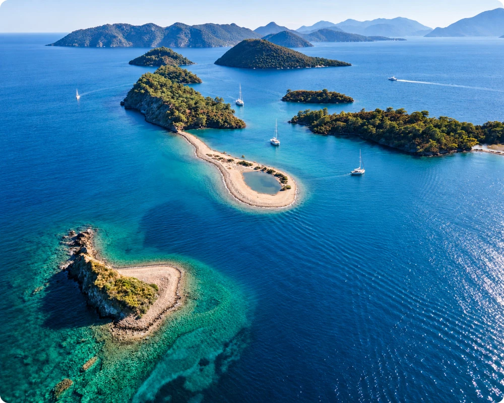 Vue aérienne de la baie de Göcek en Turquie, avec ses îlots, ses eaux turquoise et plusieurs voiliers au mouillage.