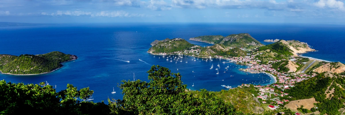 Vue panoramique sur la baie des Saintes en Guadeloupe avec des voiliers et des collines verdoyantes